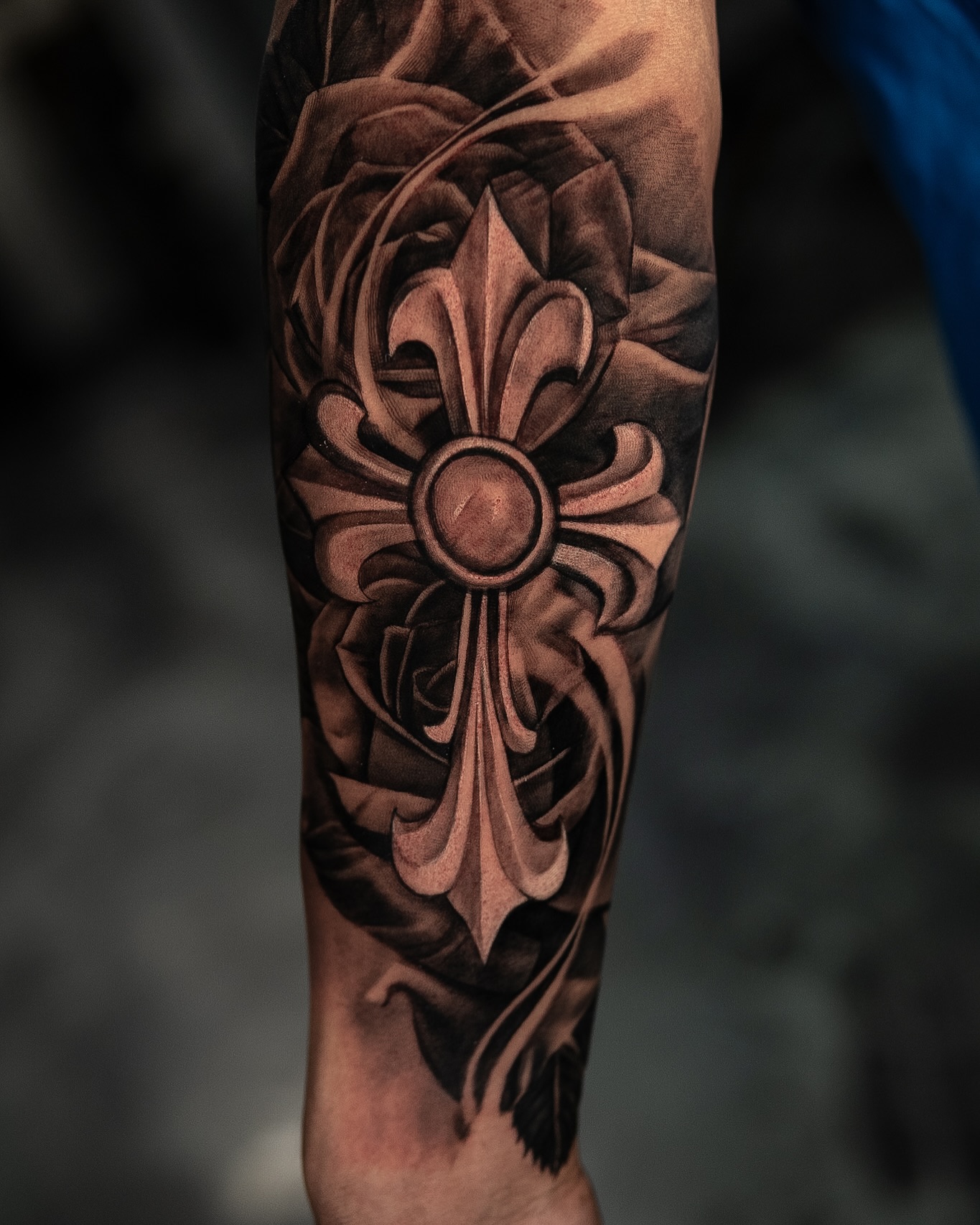 Tatuaje realista de cruz con flor de lis y rosas en antebrazo, black and gray