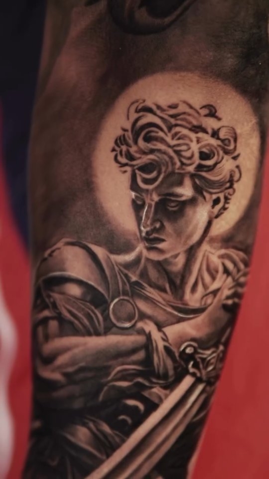 Tatuaje realista de figura clásica con espada en antebrazo, black and gray